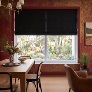 Black Roman Shades in a Dining Room with Textured Red Walls and Wooden Dining Table