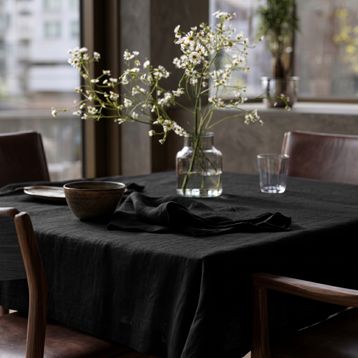 Black Square Linen Tablecloth in a Contemporary Dining Room with Brown Leather Chairs and Large Windows