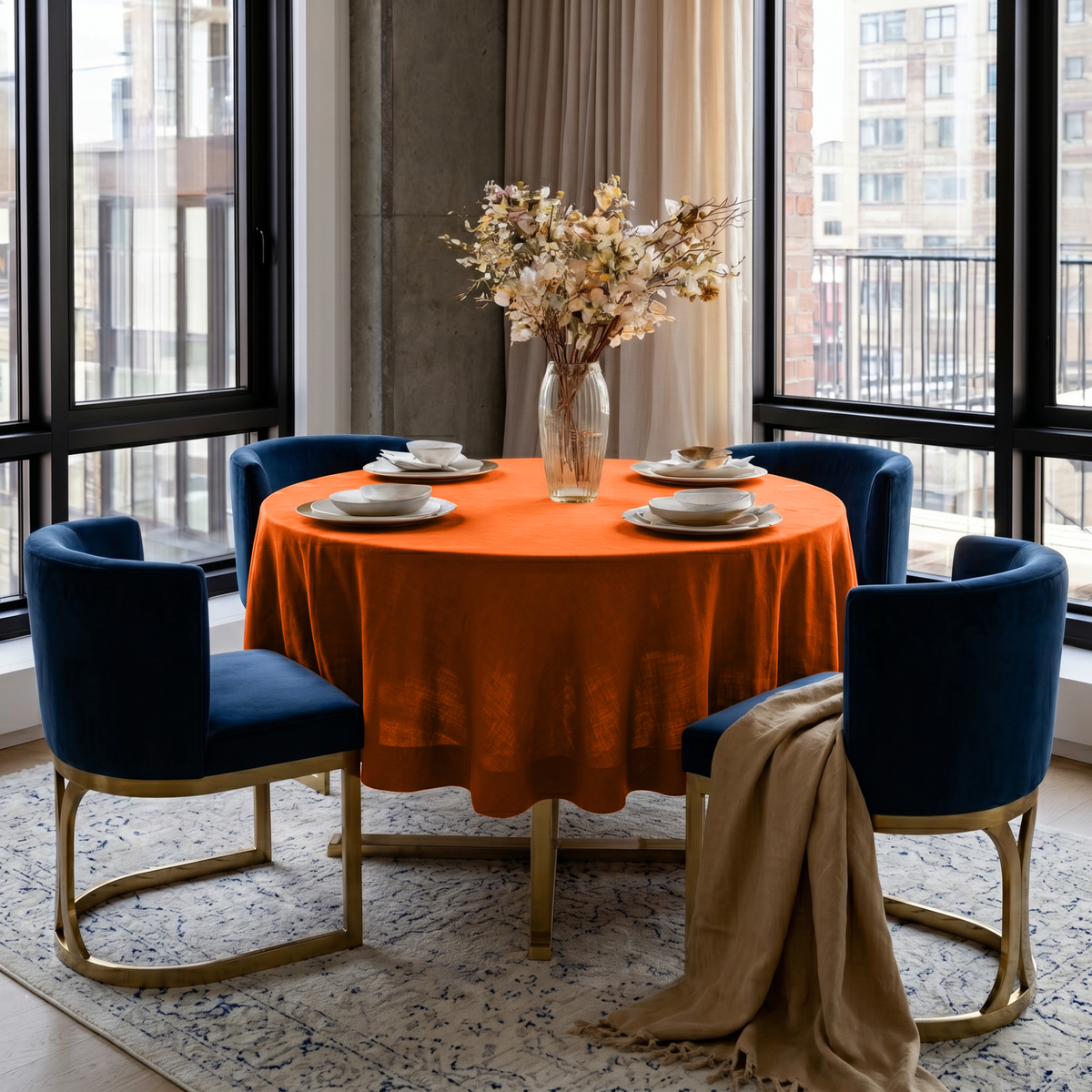 Burnt Orange Linen Round Tablecloth in a Modern City Dining Room with Concrete Walls and Navy Velvet Chairs
