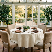 Cream Linen 84 Inch Round Tablecloth in a Bright Garden Dining Room with Bouclé Chairs