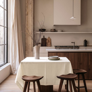 Cream Square Linen Tablecloth in a Modern Kitchen with Walnut Cabinetry and Floor-to-Ceiling Window