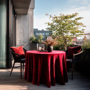 Dark Deep Red Velvet Round Tablecloth in a Balcony Dining Setting with Black Wicker Chairs and Red Cushions