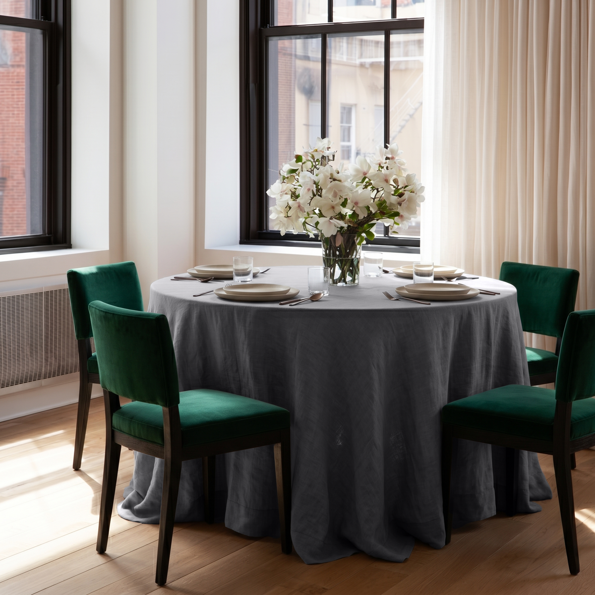 Dim Grey Linen 90 Inch Round Tablecloth in a Bright City Dining Room with White Walls and Emerald Green Velvet Chairs