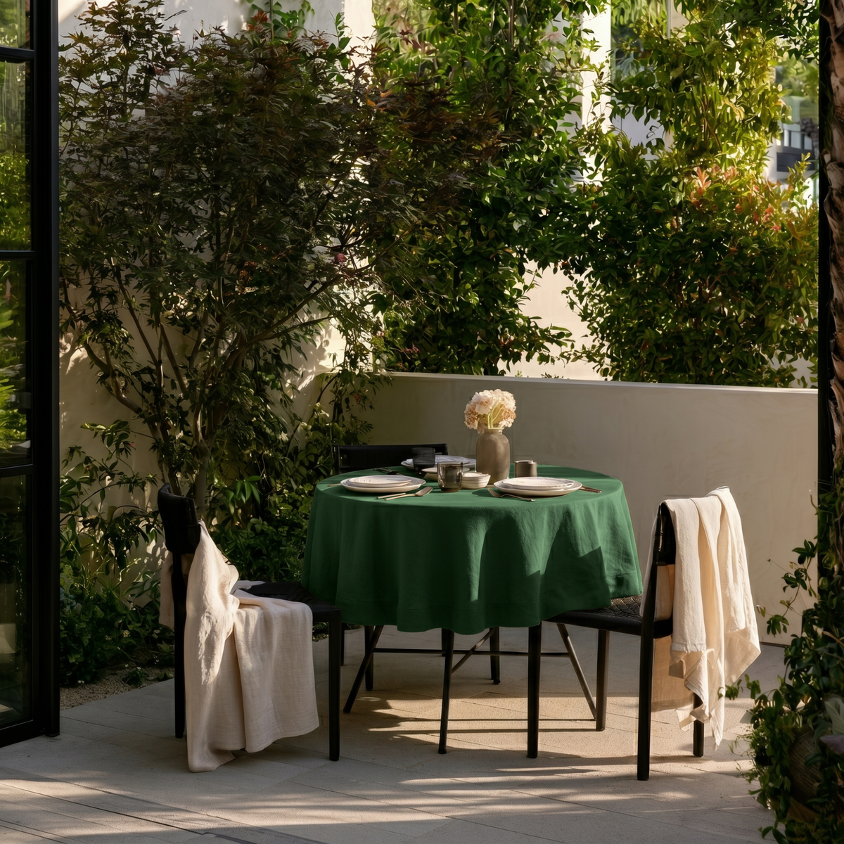 Forest Green Linen Round Tablecloth in a Garden Patio Dining Space with Soft Ivory Walls and Cream Linen