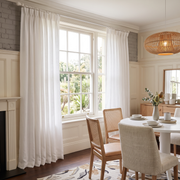 Heavy Weight Off-White Linen Pinch Pleat Dining Room Curtain in a Transitional Dining Room with Cream Paneled Walls, a Woven Pendant Light and Cane Back Chairs - Cotton Lining