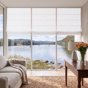 Off-White Roman Shades in a Living Room with Light Neutral Walls and a Beige Armchair
