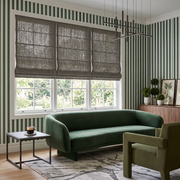 Heavy Natural Roman Shade in a Modern Living Room with Green Striped Wallpaper and a Velvet Sofa