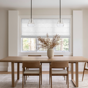 Off-White Roman Shades in a Dining Room with White Walls and a Wooden Dining Table