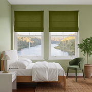 Moss Green Roman Shades in a Light Green Bedroom with White Bedding and Green Armchair