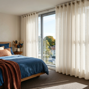 Cream Linen Grommet Curtains in a Bright Bedroom With Blue Bedding and Large Sunlit Windows