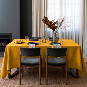 Mustard Yellow Rectangular Linen Tablecloth in a Contemporary Dining Room with Dark Upholstered Chairs and Sheer Curtains