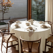 Cream Linen Round Tablecloth in a Sunlit Dining Room with Natural Woven Chairs