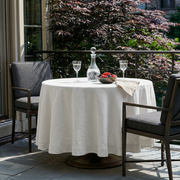 Off-White Linen Round Tablecloth in an Outdoor Balcony Dining Setting with Garden Greenery and Grey Accents