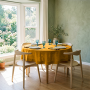 Mustard Yellow Linen 72 Inch Round Tablecloth in a Sunlit Dining Room with Sage Green Plaster Walls and Light Wood Chairs