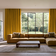 Mustard Yellow Linen Grommet Extra Long Curtains in a Modern Living Room with Large Mustard Yellow Sectional Sofa With Matching Throw Pillows, a Low Wooden Coffee Table, and a Textured Beige Rug