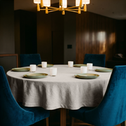 Natural Linen 72 Inch Round Tablecloth in a Warm Dining Room with Dark Wood Walls and Teal Velvet Chairs