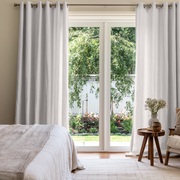 Off-White Heavy Weight Linen Grommet Extra Long Curtains in a Contemporary Bedroom with Garden Views and Natural Wood Accents