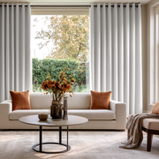 Off-White Velvet Grommet Extra Long Curtains in a Bright, Modern Living Room with Beige Sofa, Orange-Brown Pillows, and a Round Coffee Table