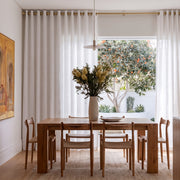 Off-White Linen Grommets Curtains In A Contemporary Dining Room With White Walls And A Light Oak Dining Table Facing An Outdoor Patio View.