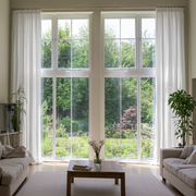 Off-White Linen Pencil Pleat Extra Long Curtains in a Bright Contemporary Living Room with Tall Windows and Garden Views