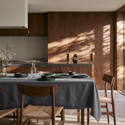 Dim Grey Rectangular Linen Tablecloth in a Modern Dining Room with Walnut Cabinetry and Woven Chairs