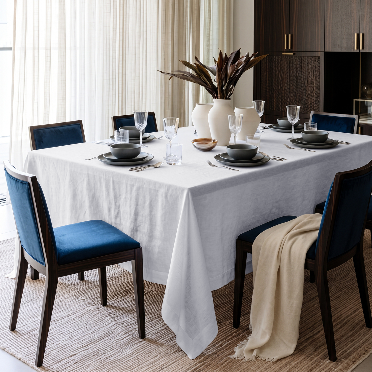 White Rectangular Linen Tablecloth in a Contemporary Dining Room with Blue Upholstered Chairs and Dark Wood Cabinetry