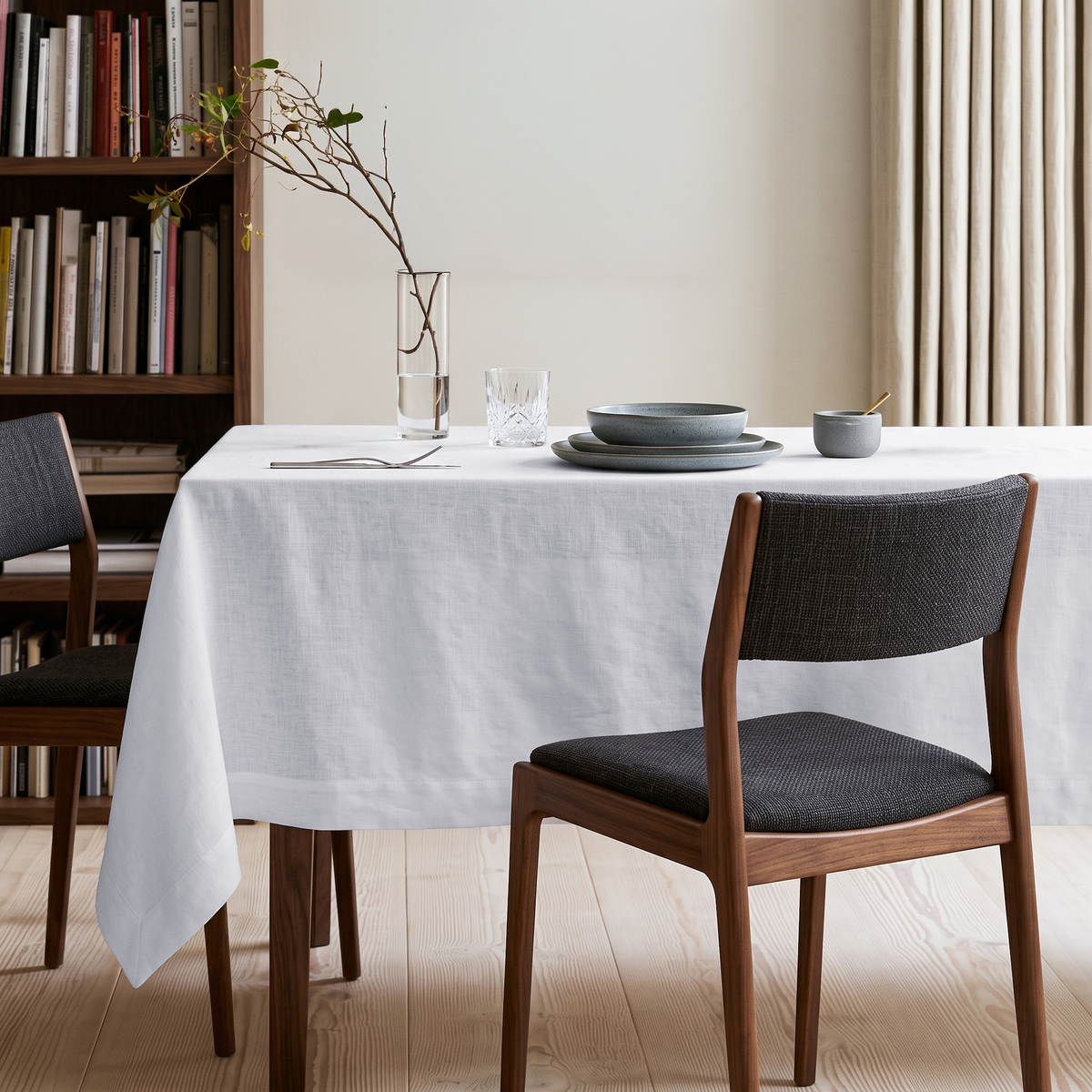White Rectangular Linen Tablecloth in a Minimalist Dining Room with Built-In Bookshelves and Walnut Chairs