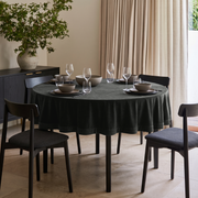 Dark Grey Round Velvet Tablecloth in a Contemporary Dining Room with Beige Curtains and Black Wood Accents