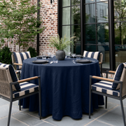 Royal Blue Linen 70 Inch Round Tablecloth in a Patio Dining Space with Brick Walls and Navy Striped Accents