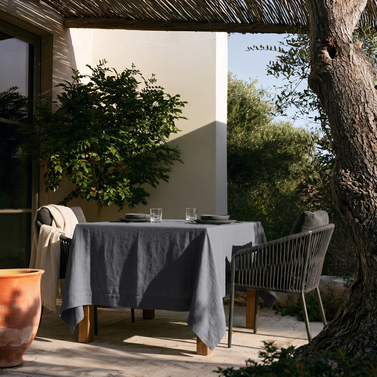 Dim Grey Square Linen Tablecloth on a Mediterranean Outdoor Patio with Olive Trees and Woven Pergola