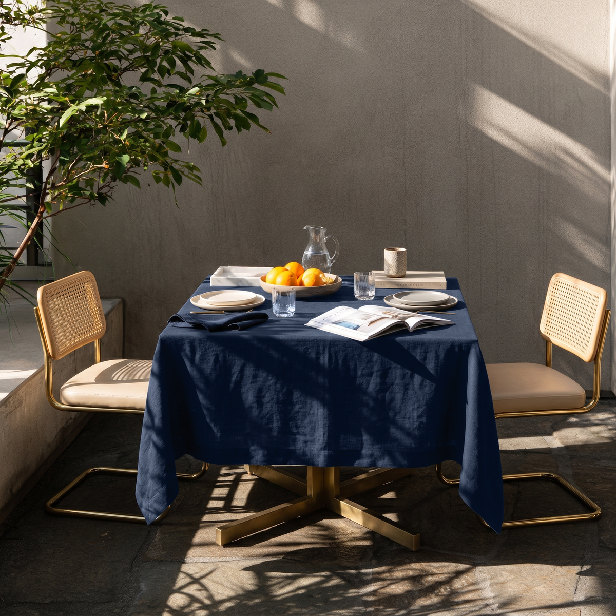Royal Blue Square Linen Tablecloth on a Contemporary Outdoor Patio with Cane Chairs and Textured Concrete Walls