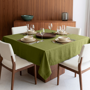 Moss Green Square Linen Tablecloth in a Contemporary Dining Room with Walnut Wood Paneling and Cream Upholstered Chairs