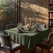 Sage Green Square Linen Tablecloth in a Rustic Contemporary Dining Room with Exposed Brick Walls and Dark Upholstered Chairs