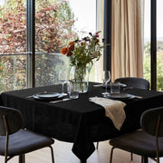 Black Square Linen Tablecloth in a Bright Contemporary Dining Room with Floor-to-Ceiling Windows and Beige Curtains