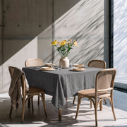 Dim Grey Square Linen Tablecloth in a Modern Dining Room with Cane Chairs and Concrete Walls