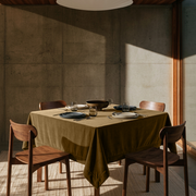 Olive Brown Square Velvet Tablecloth in a Contemporary Dining Room with Concrete Walls and Wooden Chairs