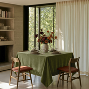 Olive Green Square Velvet Tablecloth in a Modern Dining Room with a Concrete Fireplace and Sheer Curtains