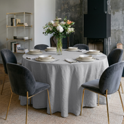 Stone Grey Linen 70 Inch Round Tablecloth in a Modern Dining Room with Concrete Fireplace and Charcoal Velvet Chairs